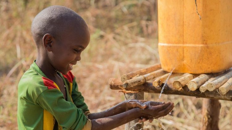 Un bambino africano prende dell'acqua da un contenitore