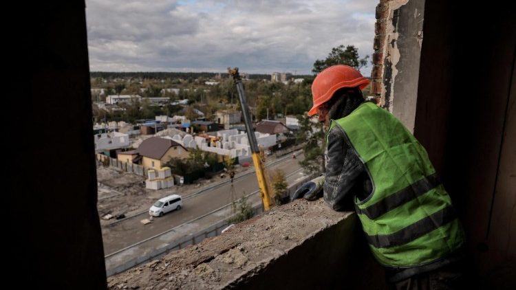 यूक्रेन के कीव शहर में एक ध्वस्त इमारत से झांकता एक व्यक्ति