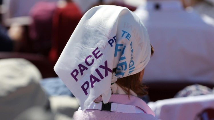 Una donna indossa un fazzoletto con la scritta "pace"