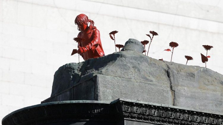Anti-Kriegskunstwerk, in Kyiv installiert: Skulptur eines Mädchens, das auf einem ehemaligen Sowjet-Denkmal Blumen pflanzt. Künstler: James Colomina.