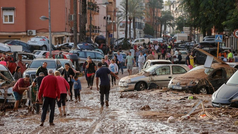 Moradores caminham por uma rua coberta de lama no município de Paiporta, atingido por enchentes, na província de Valência, Espanha, em 30 de outubro de 2024. EPA/MANUEL BRUQUE