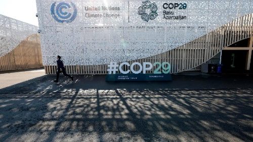 Um participante passa pelo banner de boas-vindas do lado de fora do local da Conferência das Nações Unidas sobre Mudanças Climáticas, COP29, em Baku, Azerbaijão.