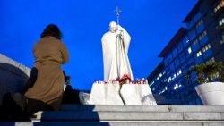 Frau im Gebet vor der Statue Johannes Paul II. im Vorhof der Gemelli-Klinik