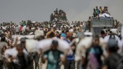 Palestinos deslocados internamente carregam sacos de farinha perto de um ponto de distribuição de alimentos em Zikim, norte da Faixa de Gaza, 8 de agosto de 2025.