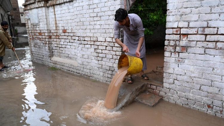  man clear water from a home flooded by heavy rain in Peshawar, Khyber Pakhtunkhwa province, Pakistan