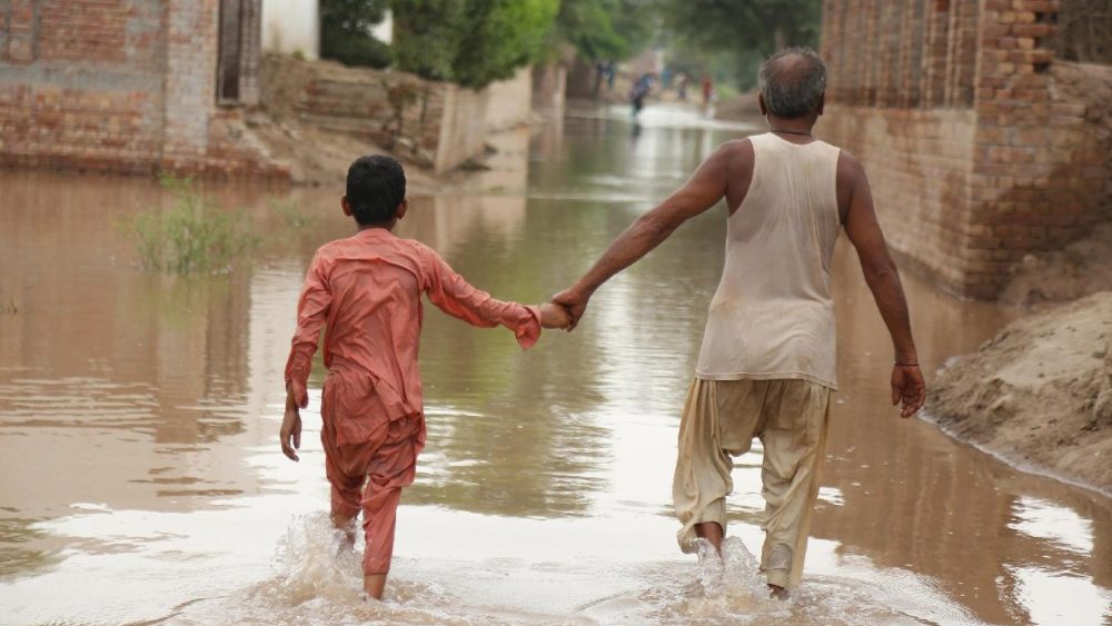 Pessoas atravessam uma área inundada após a elevação das águas do rio Chenab, no distrito de Multan, província de Punjab, Paquistão, em 2 de setembro de 2025. Pelo menos 33 pessoas morreram e mais de 1,4 milhão foram afetadas no Paquistão.
