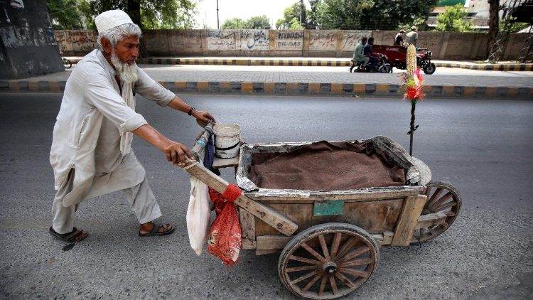 Un anziano venditore ambulante spinge il suo carretto di legno sul ciglio di una strada a Peshawar, in Pakistan.
