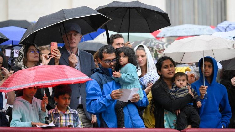 बारिश के बीच पवित्र मिस्सा में भाग लेते हुए विश्वासीगण