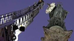 Los bomberos colocan flores en los brazos de María en la Plaza de España