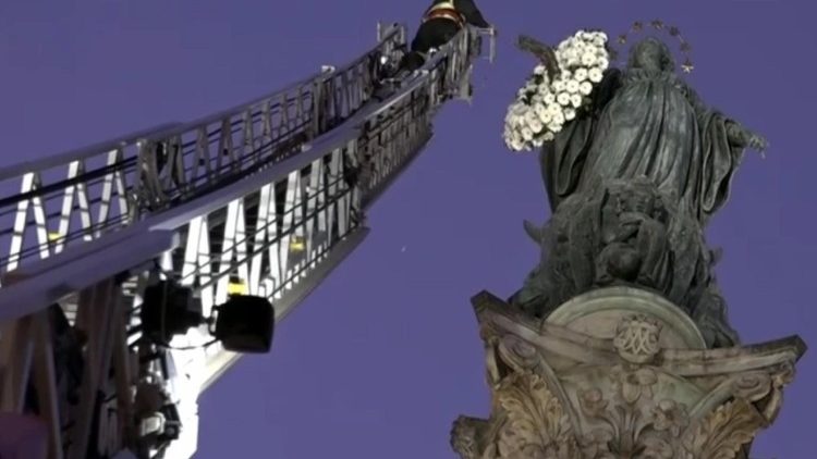Los bomberos colocan flores en los brazos de María en la Plaza de España