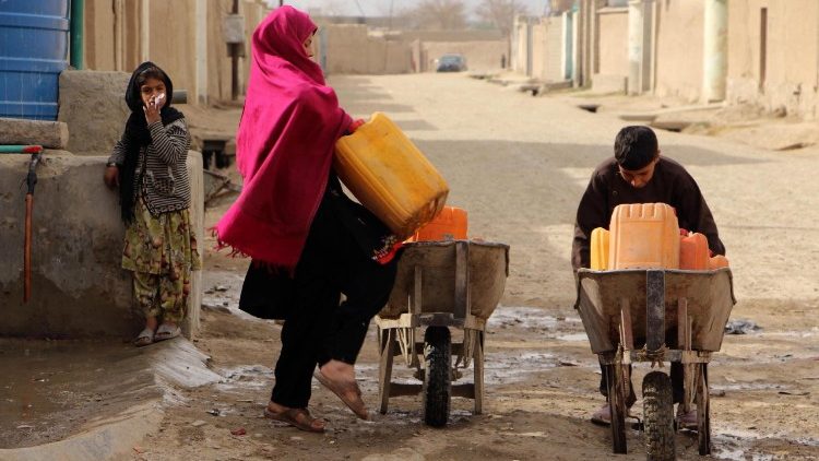 Una famiglia afghana intenta a trasportare taniche d'acqua a Kandahar