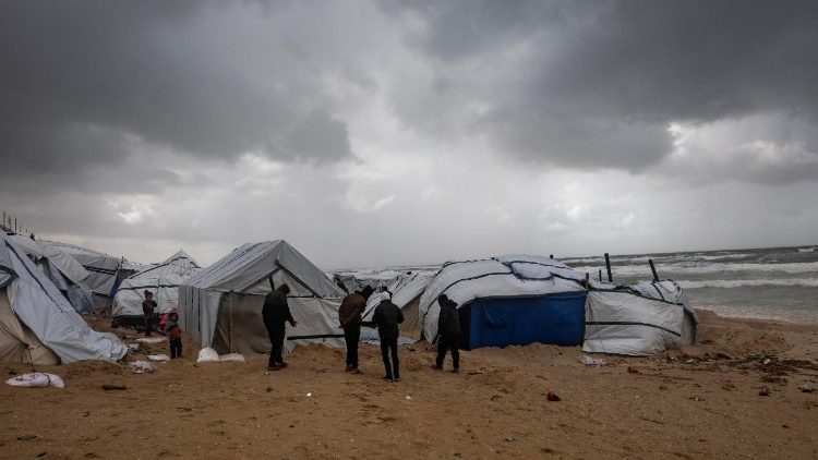 Des Palestiniens déplacés inspectent leurs tentes sous une pluie battante à l'ouest de la ville de Khan Younès, dans le sud de la bande de Gaza, le 13 janvier 2026.
