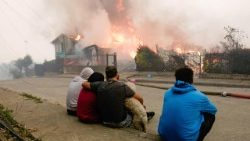 Membros de uma família observam sua casa afetada pelos incêndios florestais em Penco, Chile, em 18 de janeiro de 2026. Um total de 16 pessoas morreram em diversos incêndios florestais que ainda queimam no sul do Chile, nas regiões de Nuble e Biobío, conforme relatado pelo Ministro da Segurança Pública, Cordero. EPA/PABLO HIDALGO