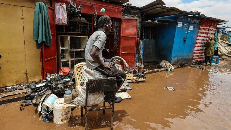 A Kenyan man sits on his salvaged auto spares outside his damaged shop after it was flooded at Grogon garage area