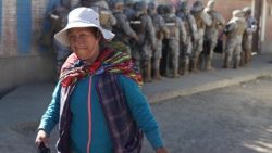 Una donna passa accanto a membri delle Forze Armate boliviane durante un'operazione per sgomberare un blocco stradale nel comune di Carreras