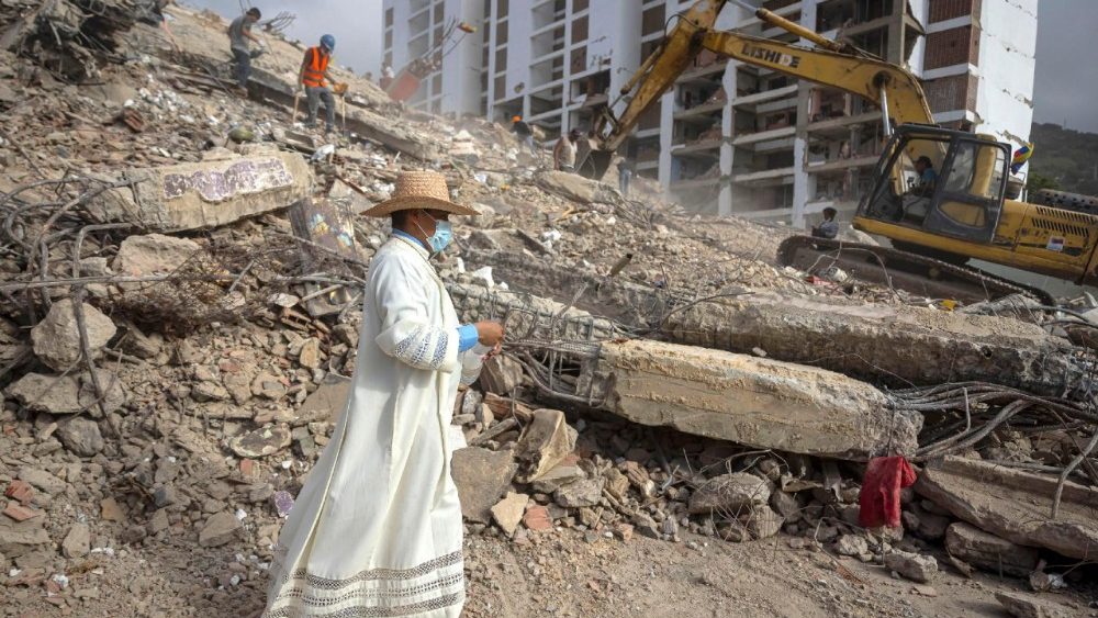O padre Omar Perez Gabino percorre um trajeto para acompanhar com orações as famílias, voluntários e socorristas que continuam o trabalho de recuperação de corpos presos sob os escombros após os terremotos gêmeos de 24 de junho em Caraballeda, Venezuela, em 17 de julho de 2026 (foto divulgada em 18 de julho de 2026). EPA/MIGUEL GUTIERREZ