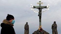 Ein einsamer Passant mit Maske auf der Prager Karlsbrücke