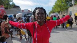 Rose chora enquanto pessoas deslocadas pela violência da guerra de gangues em Cité Soleil caminham pelas ruas do bairro de Delmas após deixarem a Praça Hugo Chaves, em Porto Príncipe. (REUTERS/Ralph Tedy Erol)
