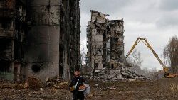 Ucraniana caminha desolada em meio a prédios de apartamentos em ruínas em Mariupol. REUTERS/Alexander Ermochenko