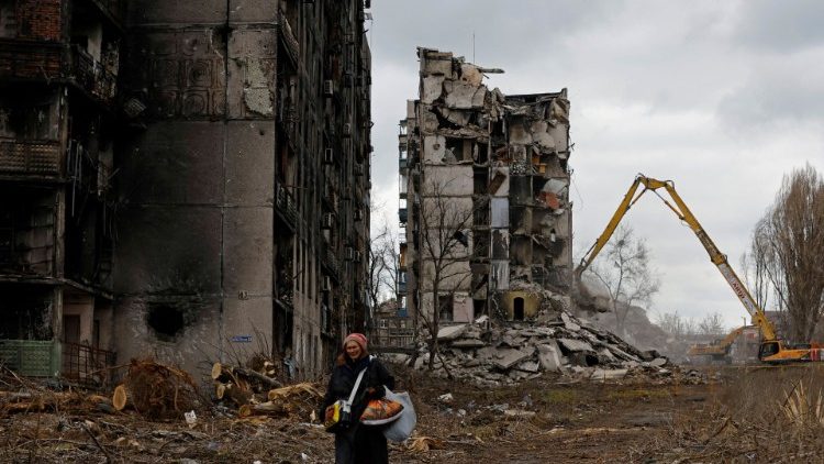 Mulher caminha em meio a escombros na cidade de Mariupol, em 15 de fevereiro de 2023. (REUTERS/Alexander Ermochencko)