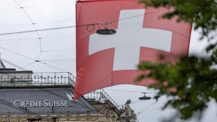 A Swiss flag is seen in front of a logo of Swiss bank Credit Suisse in Zurich
