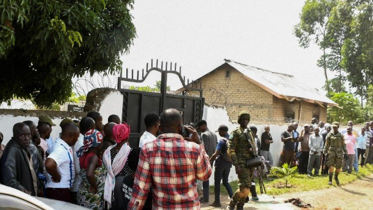 Menschen stehen vor der abgeschirmten Mpondwe Lhubirira Secondary School, in der der Angriff in der Nacht von Freitag auf Samstag verübt wurde
