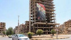 Vehicles pass near a poster depicting Syria's President Bashar al-Assad in Douma