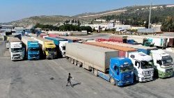 संयुक्त राष्ट्र विश्व खाद्य कार्यक्रम (डब्ल्यूएफपी) से सहायता ले जाने वाले ट्रक बाब अल-हवा क्रॉसिंग पर खड़े हैं
