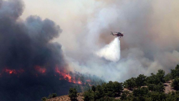 Ein Löschhubschrauber wirft Wasser über dem brennenden Wald auf Rhodos ab
