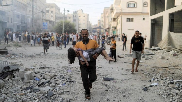 Palestinian man carries a wounded girl at the site of Israeli strikes in Khan Younis
