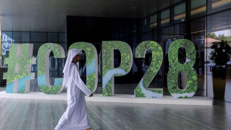 A person walks past a "#COP28" sign in Dubai