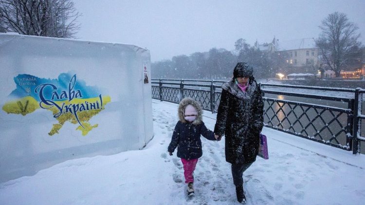 Uma mulher e uma criança caminham às margens do rio Uzh durante forte nevasca em Uzhhorod, novembro de 2023. (REUTERS/Thomas Peter)