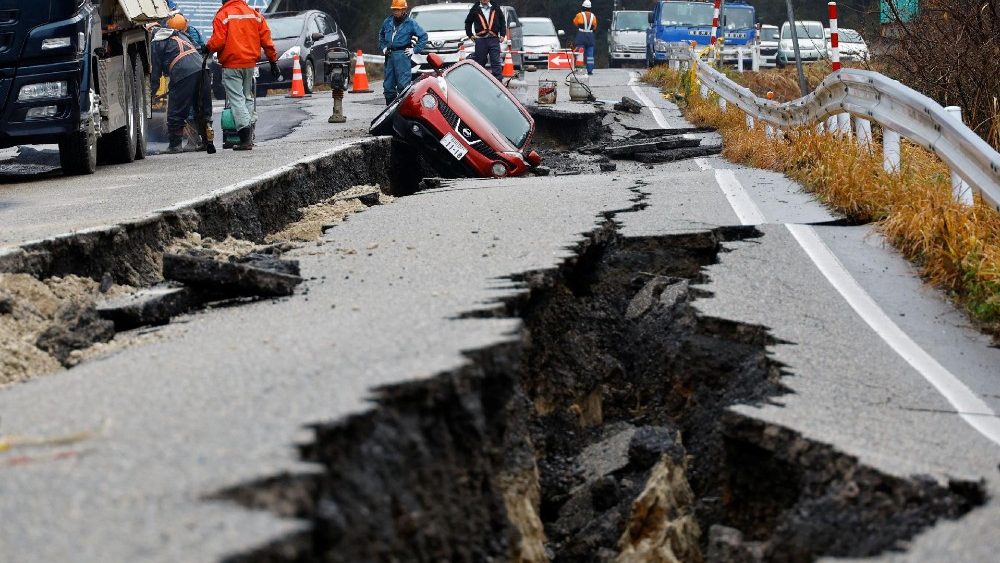 Trabalhadores reparam uma estrada ao lado de um carro preso em uma estrada quebrada, após um terremoto, perto de Anamizu, Japão, 3 de janeiro de 2024. REUTERS/Kim Kyung-Hoon