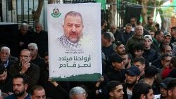 Teilnehmer einer Beerdigung mit einem Bild des getöteten Hamas-Führers al-Arouri