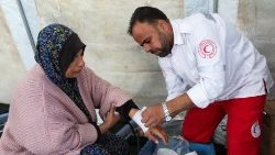 Um médico do Crescente Vermelho ajuda uma mulher palestina em Khan Younis, sul da Faixa de Gaza