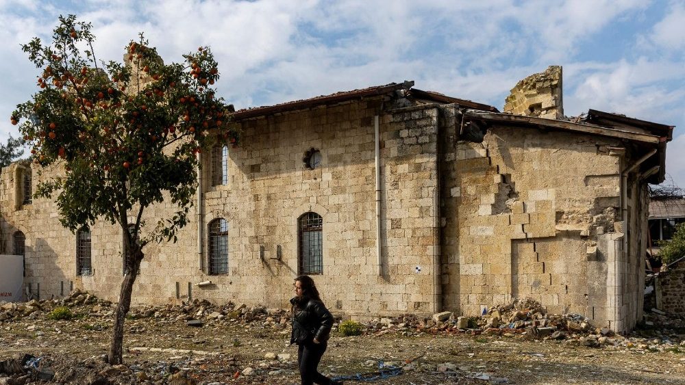 Uma mulher passa por um prédio destruído pelo terremoto do ano passado, em Hatay, Turquia, em 5 de fevereiro de 2024. O tremor de magnitude 7,8 que ocorreu nas primeiras horas de 6 de fevereiro de 2023 arrasou cidades e áreas urbanas no sudeste do país. Matou mais de 53 mil pessoas na Turquia e quase 6 mil na vizinha Síria e deixou milhões de desabrigados. REUTERS/Umit Bektas