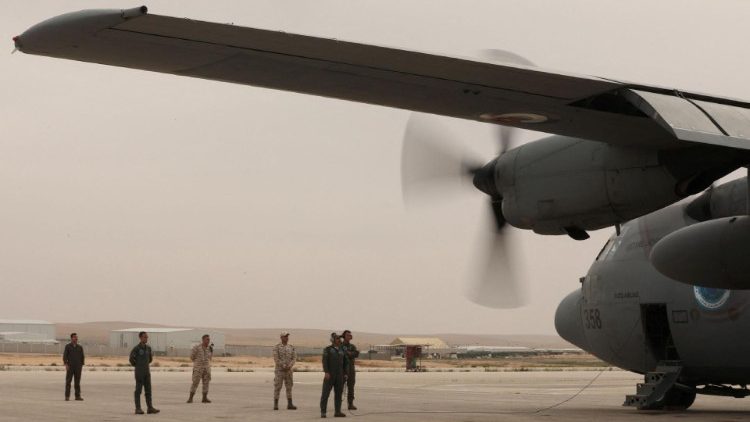 Members of Jordanian armed forces stand near a military plane loaded with aid parcels to be dropped over Gaza, in Zarqa
