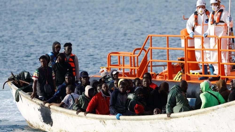 Migrants wait to disembark from a fiber boat in the port of Arguineguin