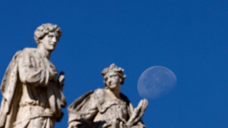 The Moon is seen behind statues of saints in the colonnade of St. Peter's Square at the Vatican