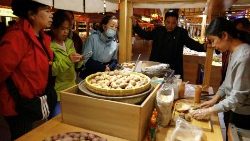 Un grupo de personas compra comida en un puesto de un mercado nocturno durante una visita organizada para la prensa en Dunhuang, China. (REUTERS)