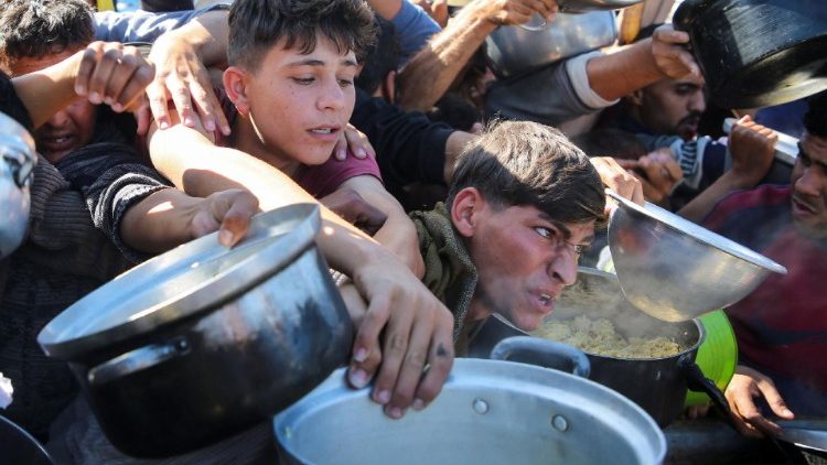 Los gazatíes se apresuran a recibir alimentos cocinados por una cocina benéfica en medio de una crisis de hambre