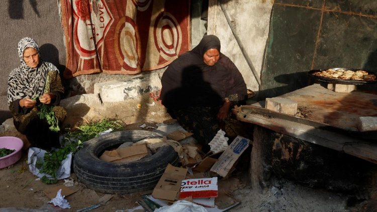 Una donna cucina per la famiglia e i vicini nel suo rifugio di fortuna, a Khan Younis, a sud della Striscia di Gaza