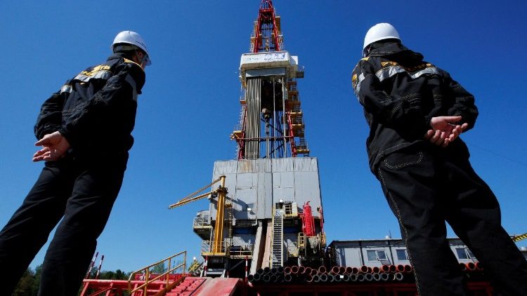 FILE PHOTO: Workers look at a drilling rig at a well pad of the Rosneft-owned Prirazlomnoye oil field outside Nefteyugansk