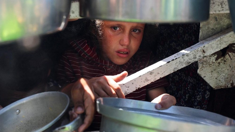 Palestinians wait to receive food from a charity kitchen, in Gaza City