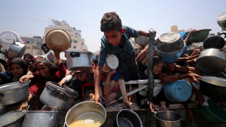 Palestinians wait to receive food from a charity kitchen, in Gaza City