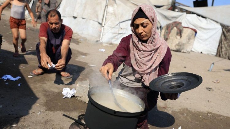 A woman cooks as displaced Palestinians who have not received humanitarian aid survive on leftover food, amid a hunger crisis, in Gaza, July 28