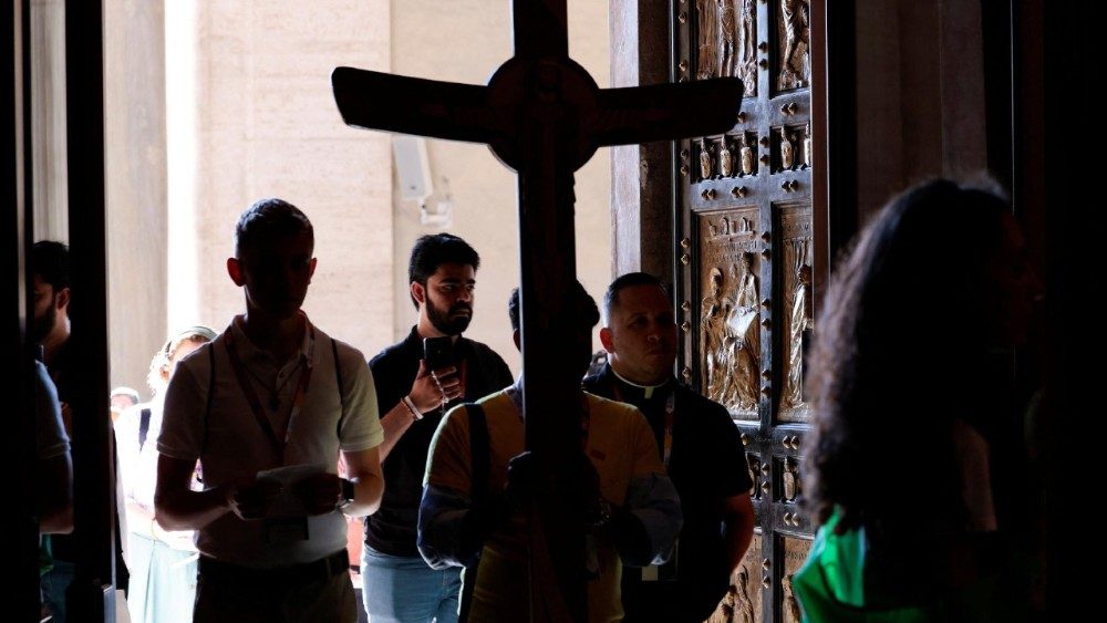 Um peregrino segurando uma cruz passa pela Porta Santa da Basílica de São Pedro durante o Jubileu da Juventude, no Vaticano, em 29 de julho de 2025. REUTERS/Remo Casilli