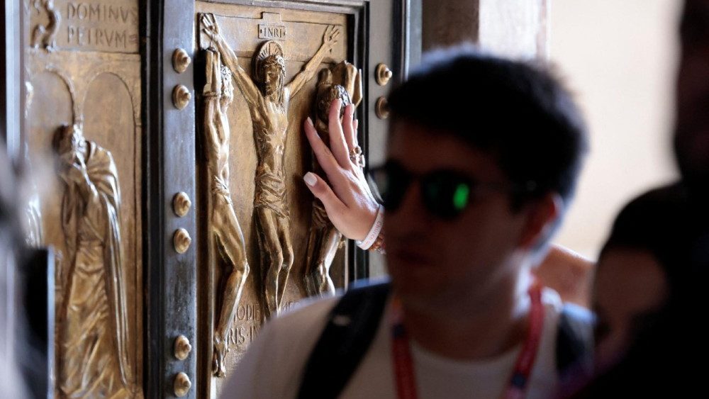 Um peregrino toca a Porta Santa da Basílica de São Pedro durante o Jubileu da Juventude, no Vaticano, em 29 de julho de 2025. REUTERS/Remo Casilli