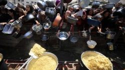 Palestinians wait to receive food from a charity kitchen, in Gaza City