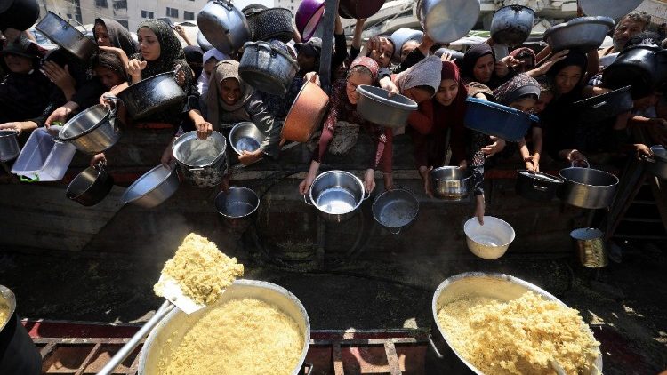 Palestinians wait to receive food from a charity kitchen, in Gaza City